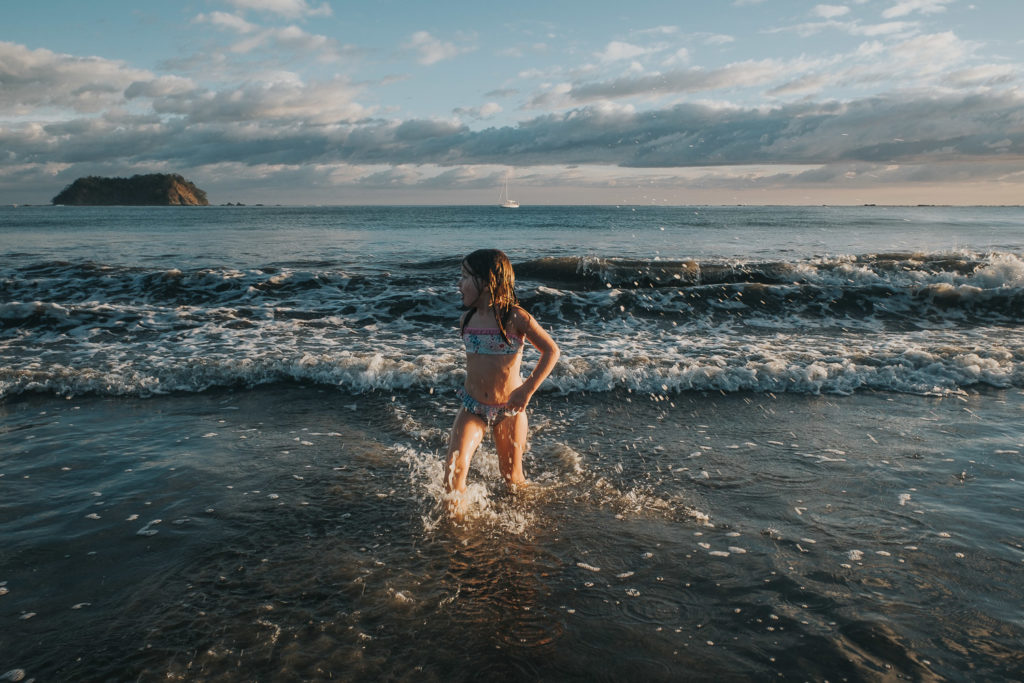 girl splashing in sea at playa samara costa rica wedding photographer