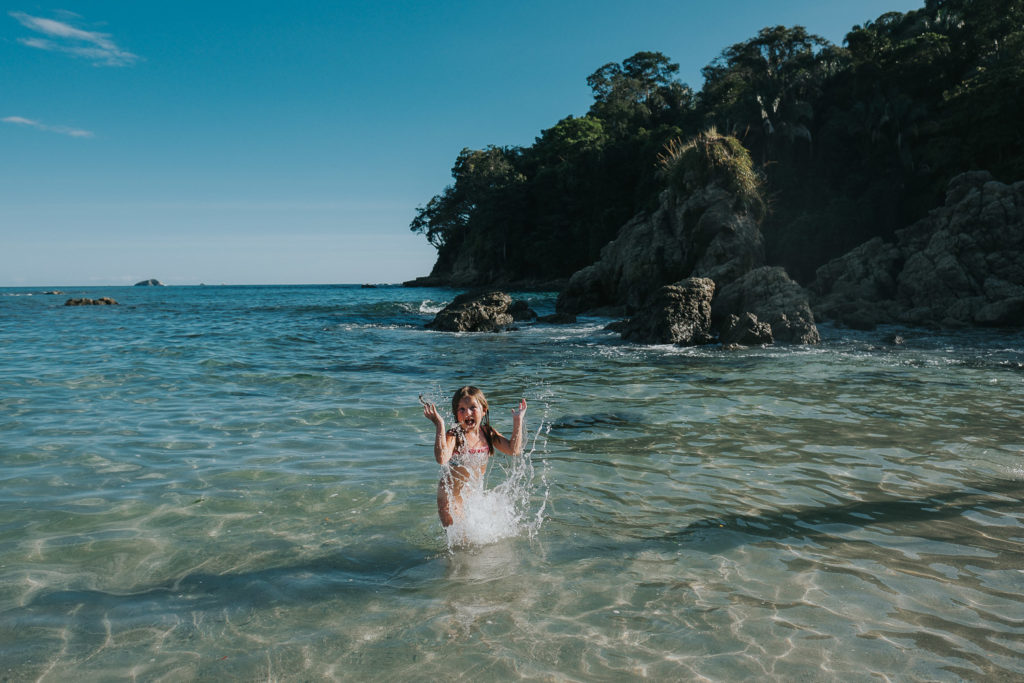 girl splashing in sea at playa manuel antonio costa rica wedding photographer