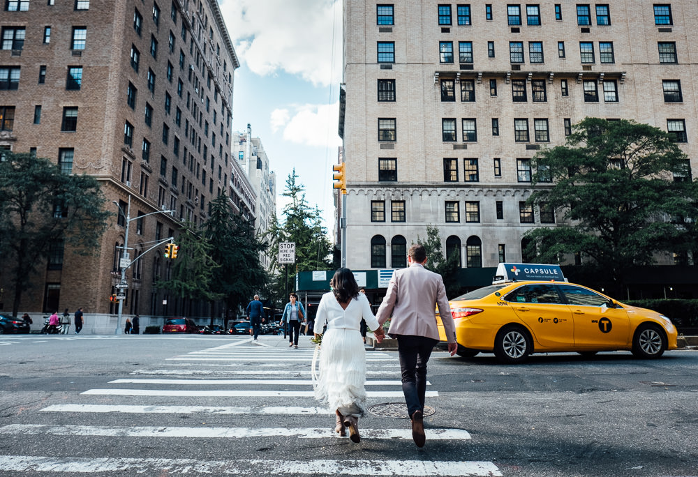 Bride and Groom crossing street in New York City with yellow taxi cab