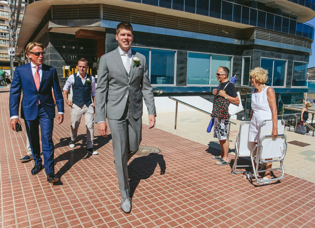 SOL Y MAR CALPE COSTA BLANCA WEDDING PHOTOGRAPHER GROOM AND GROOMSMEN WALKING TO CEREMONY BEACH PEOPLE WATCHING