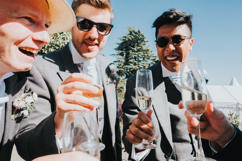 kent wedding photographer wedding guests cheers champagne glasses and laughing